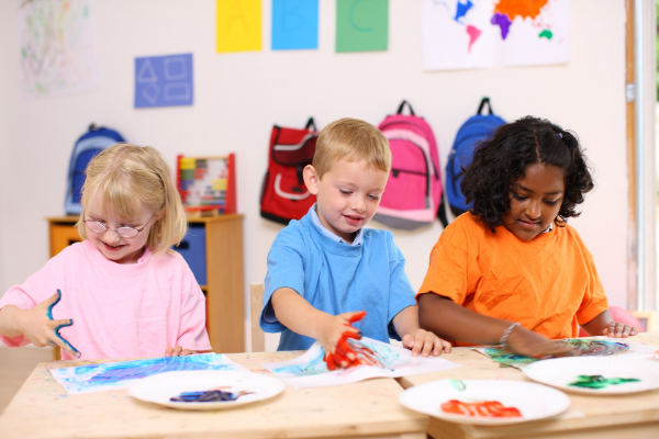 Three young children playing with finger paint