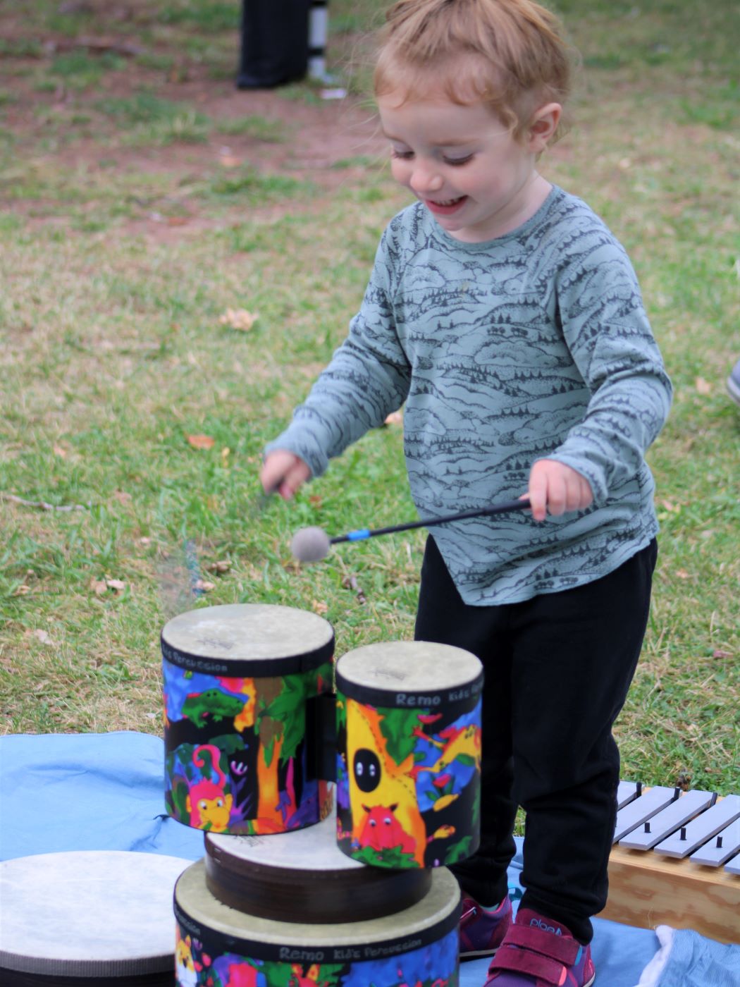 young girl playing colorful drums with a smile