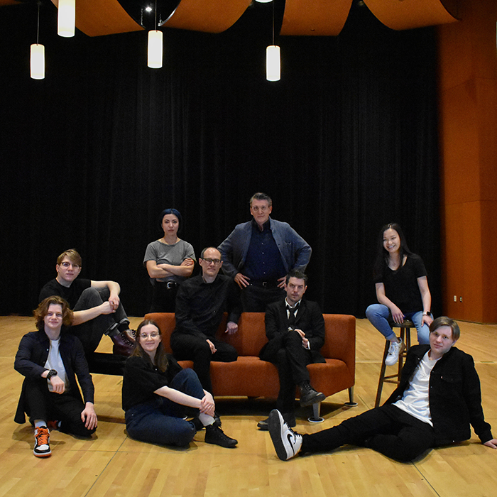 Group of 9 people sitting around an orange couch