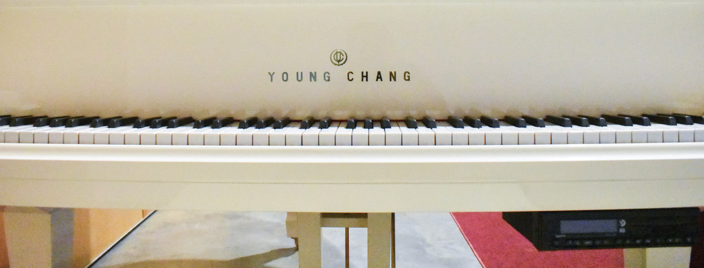 Close up image of keys on a white piano that says Young Chang