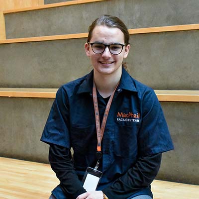 Person wearing a blue work shirt and sitting on big stairs