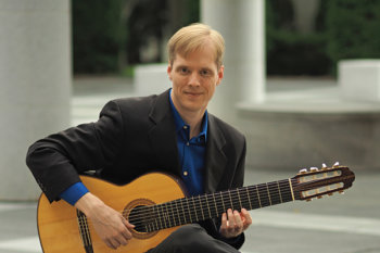 Jeff Lambert photo, smiling and holding guitar.