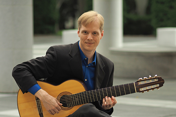 Jeff Lambert photo, smiling and holding guitar.