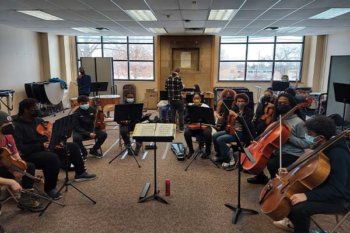 Youth orchestra students sitting in a half circle