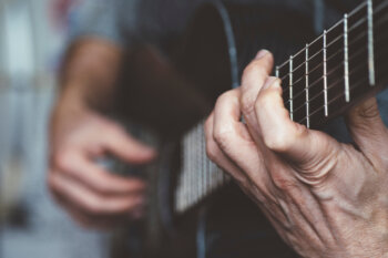 older hands playing a guitar
