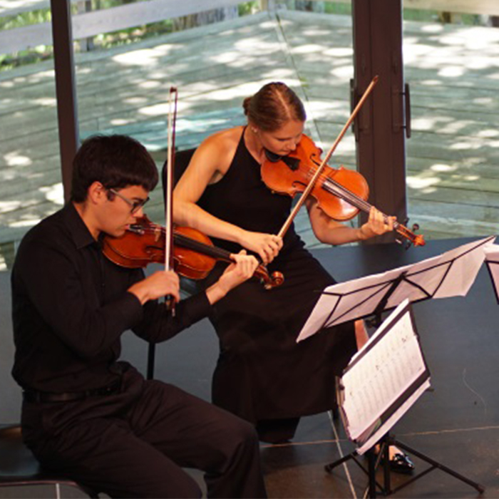 Two students playing violin on stage