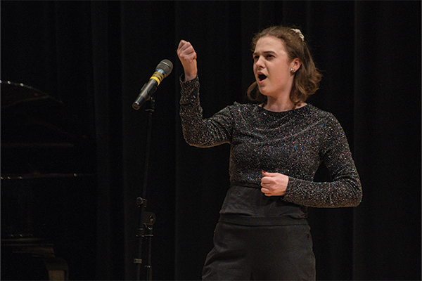 Teenager wearing black singing into a microphone