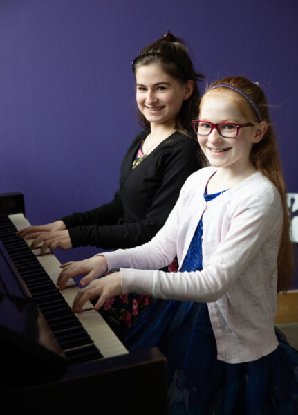 Two children playing a piano