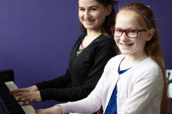 Two children playing a piano