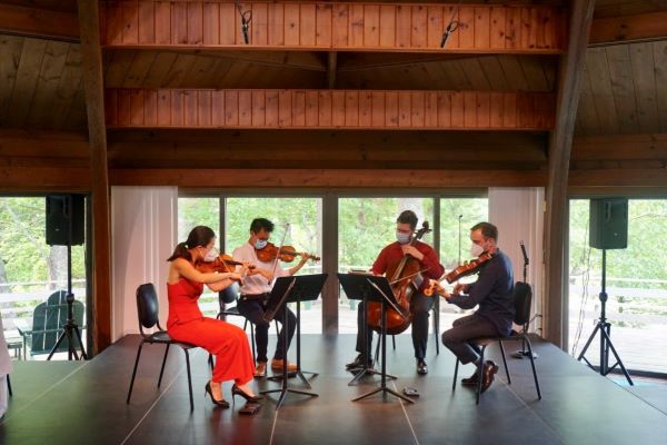 4 people playing string instruments on a stage