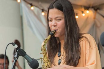 Young student playing saxophone into a microphone