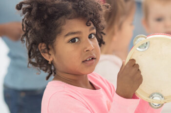 Child playing tambourine in a group setting