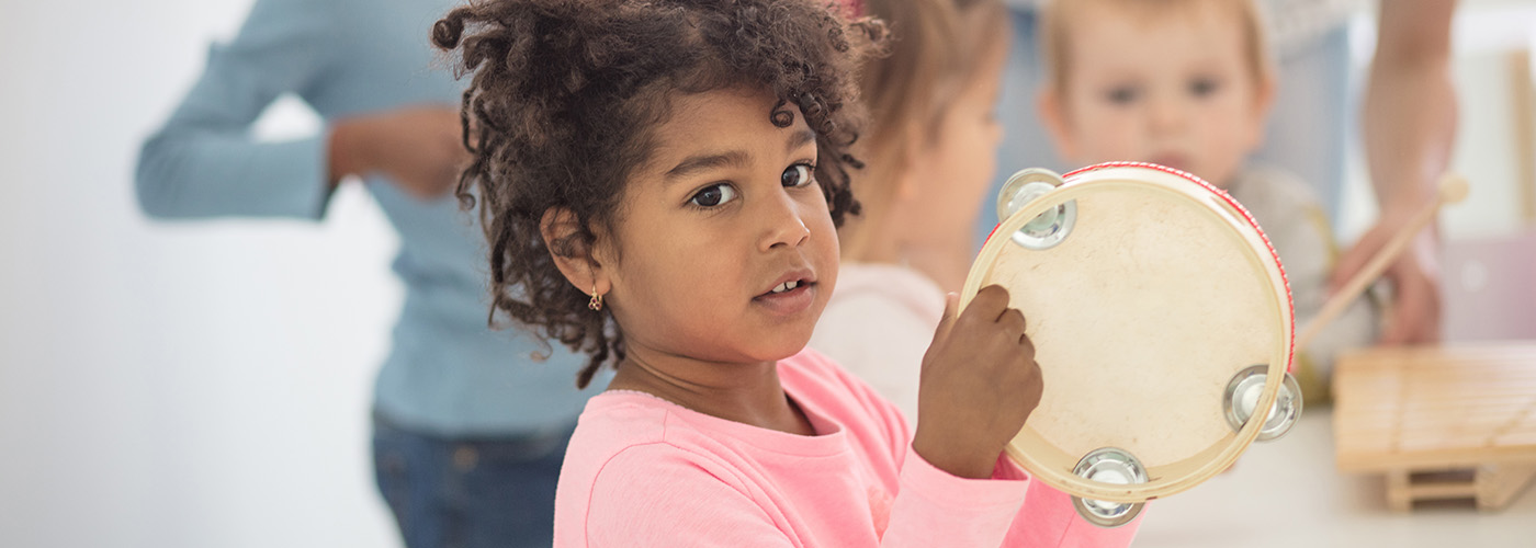 Child playing tambourine in a group setting