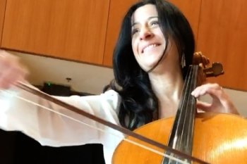 Adult playing a cello and smiling