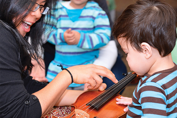 Teacher showing a violin to a young child