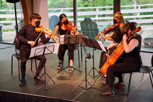 4 people on a stage playing string instruments