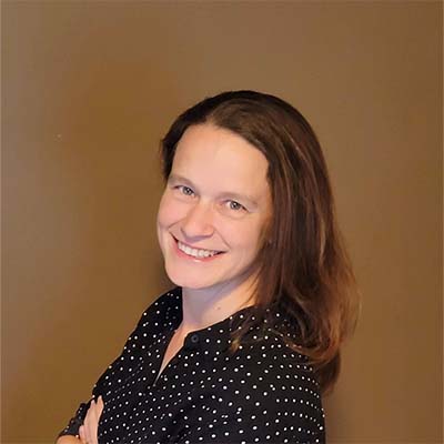 Kate's headshot. Brown hair wearing a black shirt with small white dots