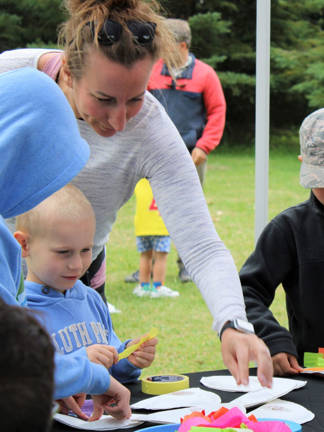 a mother and her young son making a craft at an outdoor music festival