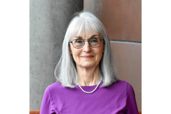 Person with shoulder length hair, wearing a purple top