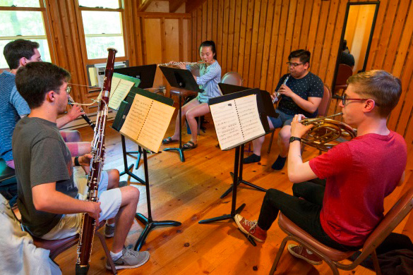 A group of young students sitting in a circle playing woodwind instruments