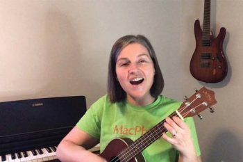 Person wearing a green shirt and holding a small guitar